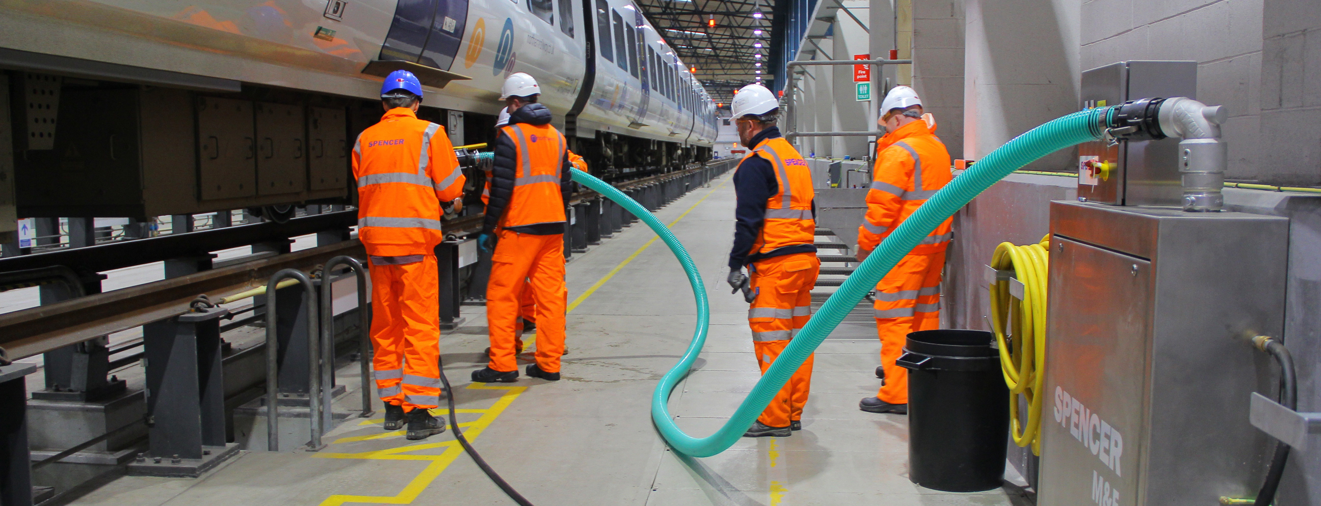 four workers fitting a CET system tube to a train